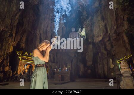 Junge Frau betet in einem buddhistischen Tempel mit Weihrauch Huyen Khong Höhle mit Schreinen, Marmorberge, Vietnam Stockfoto