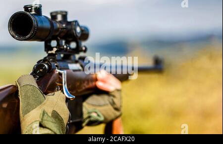 Hunter zielt. Shooter Sichtung in das Ziel. Der Mann ist auf der Jagd. Jagdgewehr jagen. Jäger. Jagdzeit. Männlich mit einer Waffe. Nahaufnahme Stockfoto