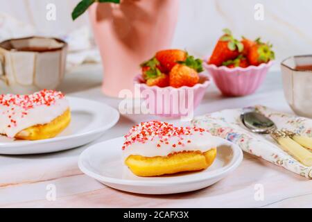 Frühstück mit süßem Donut auf weißem Teller, Erdbeere und Tasse Kaffee streuen. Stockfoto