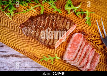 Köstliches und gesundes gegrilltes mittelseltenes Rindersteak auf Holzbrett mit Gabel. Stockfoto