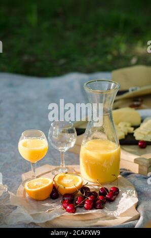 Decke mit Lebensmitteln für Sommer Picknick im Park vorbereitet. Käse, Obst, Brot, Saft und Snacks auf der Decke Stockfoto