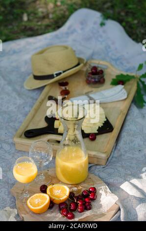 Decke mit Lebensmitteln für Sommer Picknick im Park vorbereitet. Käse, Obst, Brot, Saft und Snacks auf der Decke Stockfoto