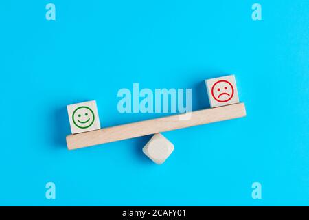 Fröhliche und traurige Smiley-Gesichter auf hölzerner Wippe. Kundenzufriedenheit, Bewertung oder positives Feedback-Konzept. Stockfoto