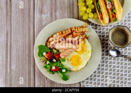 Leckeres Frühstück mit Eiern, Würstchen, Speck, Toast und einer Tasse Kaffee. Stockfoto