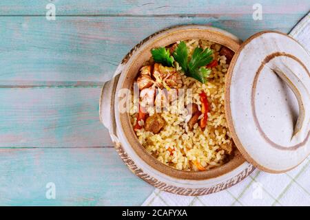 Thailändischer Reis mit Gemüse und Fleisch im Topf mit Deckel auf Holzboden. Stockfoto