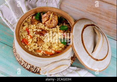 Reispilaf mit Lamm, Karotten, Knoblauch und indischen Gewürzen in Tontopf mit Deckel. Stockfoto