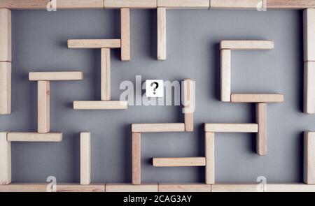 Labyrinth oder Labyrinth aus Holzblöcken mit einem Holzwürfel mit Fragezeichen in der Mitte. Geschäftsstrategie, Problemlösung, Herausforderung oder Geburtshilfe Stockfoto