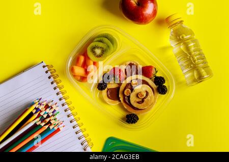 Schullunch-Box mit Pfannkuchen, frischem Obst und einer Flasche Wasser mit Vorräten. Zurück zur Schule Konzept. Stockfoto