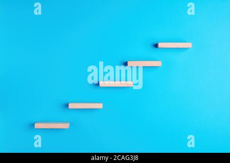 Holzblöcke bilden eine Treppe auf blauem Hintergrund. Leiter des Erfolgs, der Beförderung oder des Aufstiegs. Stockfoto