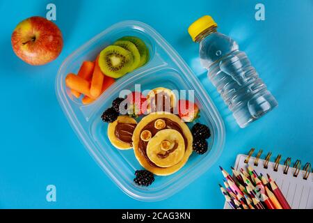 Schullunch-Box mit Pfannkuchen, frischem Obst und einer Flasche Wasser mit Vorräten. Zurück zur Schule Konzept. Stockfoto