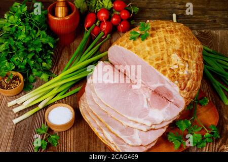 Esstisch mit gebratenen und in Scheiben geschnittenen Schinken, Gemüse und Gewürzen. Thanksgiving Day Konzept. Stockfoto