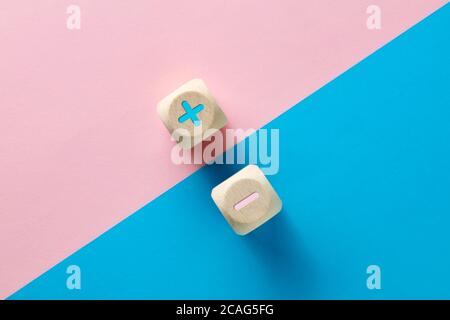 Einheit oder Gleichgewicht der Gegensätze Konzept. Negative und positive oder Plus- und Minus-Symbole auf rosa und blauem Hintergrund. Stockfoto