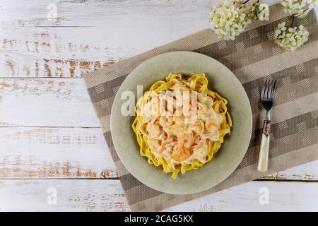 Fettuccine Pasta mit alfredo Sauce und Garnelen auf Teller mit Gabel. Stockfoto