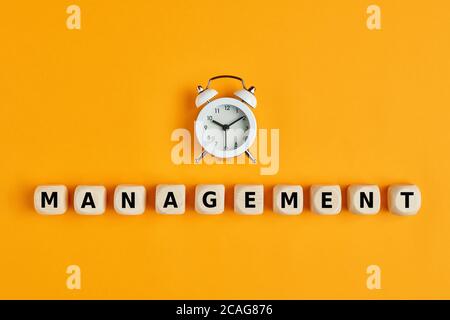 Wecker mit dem Wort-Management auf Holzwürfeln geschrieben. Konzept des Zeitmanagements in Geschäftsprojekten oder im täglichen Leben. Stockfoto