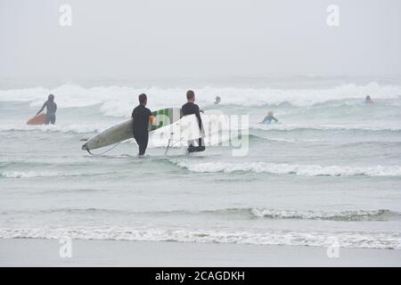 Tofino Surfer betreten das Meer an nebligen und windigen Sommertagen. Stockfoto