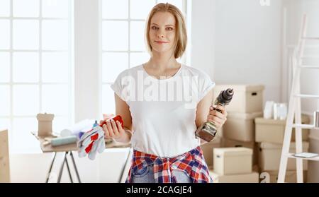 Ein junges Mädchen, das für Reparaturen gekleidet ist, steht und hält einen Schraubendreher in der Hand. Werkzeuge für Mädchen und Männer Stockfoto