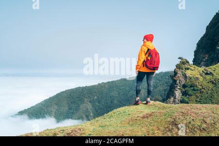 Junge weibliche Backpacker gekleidet orange wasserdichte Jacke Wandern durch die Berg über der Wolkenroute Ende Februar Auf der Insel Madeira, Portuga Stockfoto