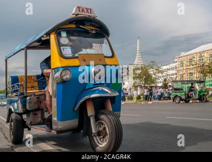 Ein typisches Tuk Tuk Taxi im historischen Zentrum von Bangkok, Thailand, mit einem der berühmtesten Tempel im Hintergrund Stockfoto