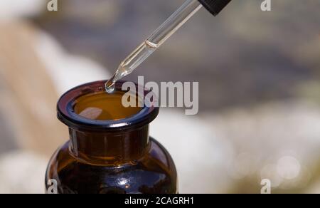 Ätherisches Öl, das aus dem Glasbehälter fällt. Stockfoto