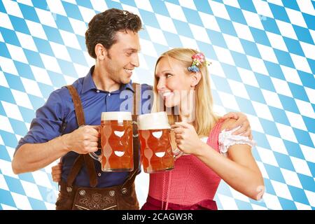 Fröhliches Paar beim Toasten mit Bier in bayerischer Tracht zum Oktoberfest Stockfoto