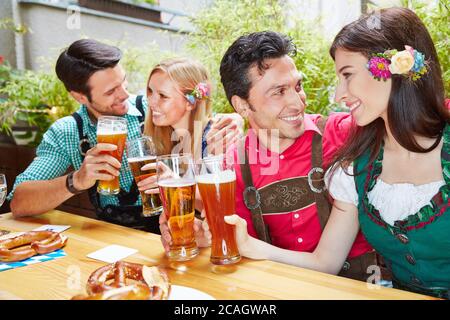 Zwei lachende Paare trinken gemeinsam im Biergarten Bier Stockfoto
