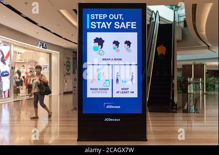 19.06.2020, Singapur, , Singapur - EINE Frau, die einen Mundschutz trägt, geht am ersten Tag an einem digitalen Bildschirm im Jewel Terminal am Changi Flughafen vorbei Stockfoto