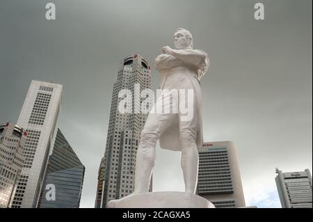 02.07.2020, Singapur, , Singapur - Dunkle Wolken hängen über der Statue von Sir Thomas Stamford Raffles entlang des Singapore River und der Skyline mit sk Stockfoto