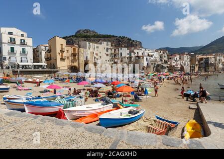 11.08.2018, Cefalu, Sizilien, Italien - Fischerboote werden am Stadtstrand festgemacht. Im Hintergrund Häuser der Altstadt, von Kalkstein überblickt Stockfoto