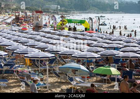 11.08.2018, Cefalu, Sizilien, Italien - Massentourismus am Stadtstrand. Touristen entspannen unter Sonnenschirmen und baden im Mittelmeer. 00U180811D023CA Stockfoto