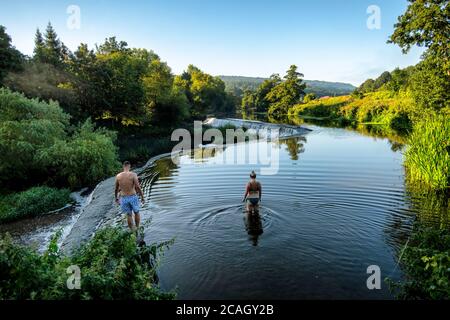 Die Menschen genießen einen frühen Morgenschwimmen in Warleigh Weir auf dem Fluss Avon in der Nähe von Bath in Somerset, wie die Temperaturen sind hoch über dem Vereinigten Königreich eingestellt. Stockfoto