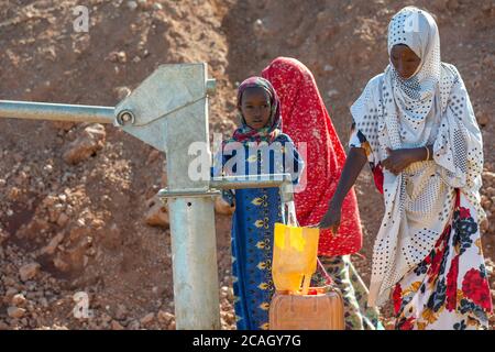 13.11.2019, Gabradahidan, Somali Region, Äthiopien - Frau, die einen gelben Wasserkanister an einer Wasserpumpe füllt, die an eine Zisterne angeschlossen ist. Wasserbauingenieurin Stockfoto