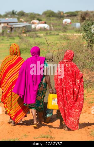 13.11.2019, Gabradahidan, Somali Region, Äthiopien - zwei Frauen tragen einen mit Trinkwasser gefüllten gelben Wasserkanister in das Dorf. Hydraulikaggregat Stockfoto