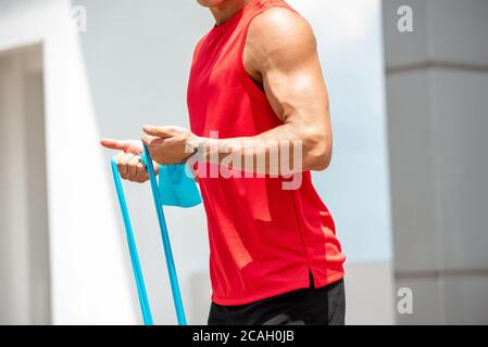 Fit muskulösen Sport Mann tun Bicep Curl Übung mit Widerstand Machen Sie im Freien bei Sonnenlicht Band Stockfoto