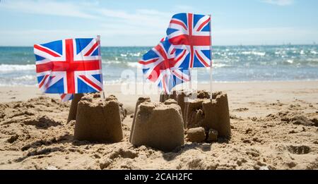 Sommer in Dorset. Poole. Zerbröckelnde Sandburgen mit Union Jacks Stockfoto