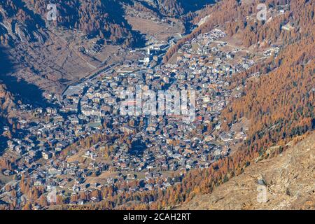 Luftaufnahme der Stadt Zermatt im Tal von der Spitze der Berge mit goldenen Bäumen und Wald an sonnigen Herbsttag, Zermatt, Wallis, Schweiz Stockfoto