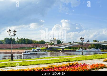 WELIKI NOWGOROD, RUSSLAND - 5. AUGUST 2016. Nowgorod Kreml mit Fußgängerbrücke und Ausflugsboot schwimmt den Fluss Volkhov Stockfoto