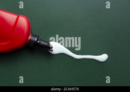 Nahaufnahme des verschütteten Leims mit einem roten Behälter Stockfoto