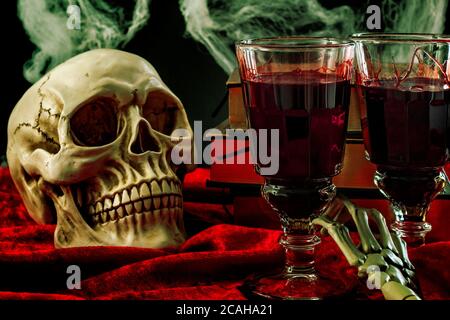 Halloween-Kulisse, Geisterhaus und Vampirdrink konzeptionelle Idee mit Totenkopf, Glas gefüllt mit Blut, Spinnweben, Vintage-Bücher und Skelett Arm auf Stockfoto