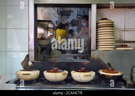 Die Tontöpfe in China werden für ein beliebtes kantonesisches Gericht verwendet, gekochter Reis mit Fleisch und Gemüse, gewürzt mit Sojasauce und Öl. Stockfoto