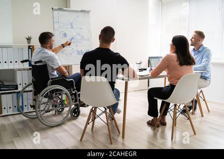 Rollstuhl Und Behinderung Im Büro. Präsentation Bei Der Arbeit Stockfoto