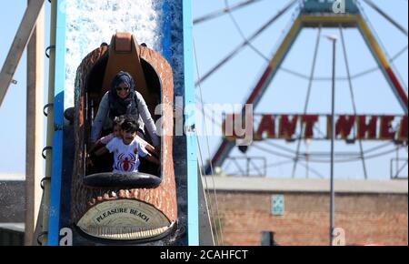 Die Leute genießen die Rundholzfahrt am Skegness Pleasure Beach, wenn das warme Wetter weitergeht. Stockfoto