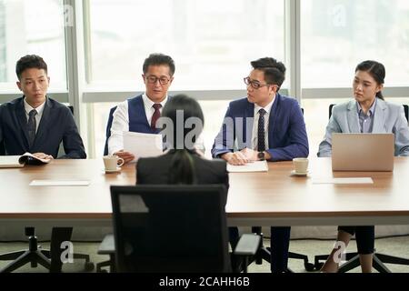 Junge asiatische Geschäftsfrau, die von einer Gruppe von Unternehmensleitern interviewt wird Stockfoto