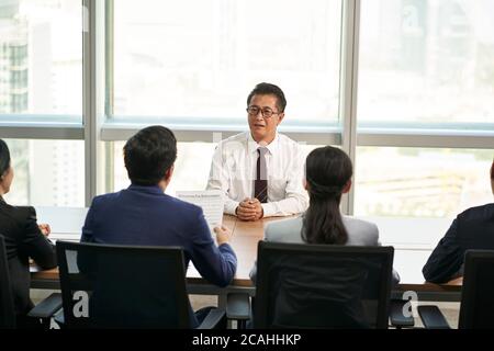 Ältere asiatische Business-Mann Arbeitsuchende wird von einer Gruppe von jungen Personalchefs interviewt