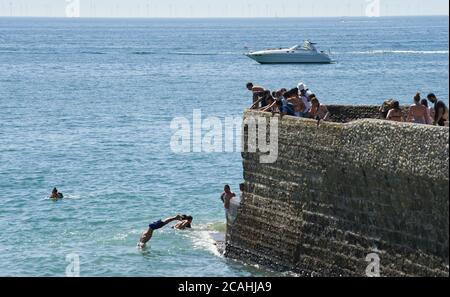 Brighton UK 1. August 2020 - Jugendliche springen und tauchen in das Meer von einem Brighton Strandpromenade Groyne an dem, was vorhergesagt wurde, dass der heißeste Tag des Jahres bisher mit Temperaturen erreichen die hohen 30 in einigen Teilen des Südostens heute sein : Kredit Simon Dack / Alamy Live Nachrichten Stockfoto