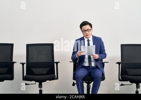 Junge asiatische männliche Arbeitssuchende Vorbereitung für Interview während warten in der Schlange Stockfoto
