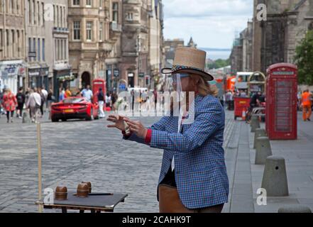 Royal Mile, Edinburgh, Schottland, Großbritannien. August 2020. 'Todd Various' Edinburgh Street Performer entscheidet, dass die Show weitergehen muss.das Fringe Festival 2020 wurde wegen der Covid-19 Pandemie abgesagt, aber heute wäre der Eröffnungstag des diesjährigen Fringe Events gewesen. Die Annullierung ist die erste seit ihrer Gründung im Jahr 1947. Todd trug ein schützendes Visier und führte Zaubertricks für ein sozial distanziertes kleines Publikum durch, denn das ist alles, was er tun darf. Während der Vorstellung musste er ständig Passanten bitten, weiter zu gehen, aber alle halbe Stunde zu seiner nächsten Show zurückzukehren. Stockfoto