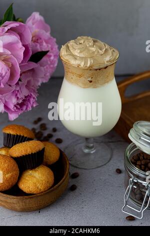 Kaffee, Milchshake und Muffins. Dalgona Coffee - das koreanische Kaffeetrink auf Holzhintergrund. Instant-Kaffee oder Espresso-Pulver mit Zucker peitscht Stockfoto