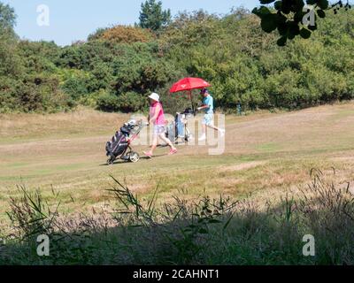 Thorpeness Suffolk, Großbritannien. August 2020. Golfer schützen mit einem Sonnenschirm, während die Temperaturen in die Mitte der 30er Jahre Grad an einem Tag Prognose, um der heißeste Tag des Jahres so weit sein. Die aktuelle heiße Phase setzt sich im Osten Englands fort. Kredit: Julian Eales/Alamy Live Nachrichten Stockfoto