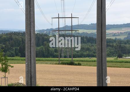 Blick zwischen zwei Stromsäulen der Stromübertragung Turm von Hochspannungs-Strom in der Mitte der Wiese zu den nächsten elektrischen Polen. Stockfoto