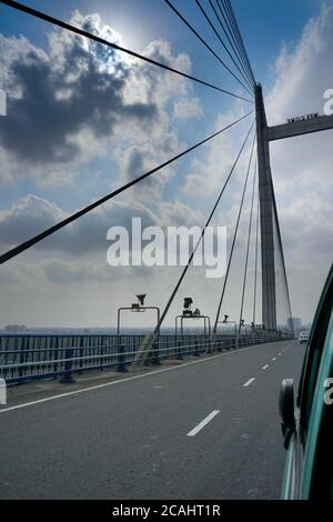 Sonnenstrahlen, die durch Wolken in blauem Himmel über der 2nd Hoogly Bridge, Kalkutta, West Bengal, Indien. Vertcial Bild. Stockfoto